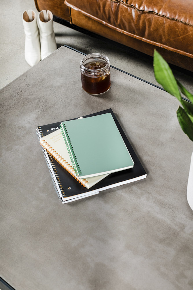 Photo of notebooks stacked on a table with a cold coffee