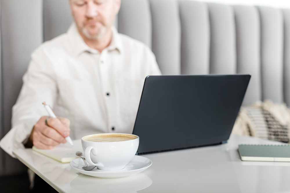 A photo of a man working at a laptop with coffee