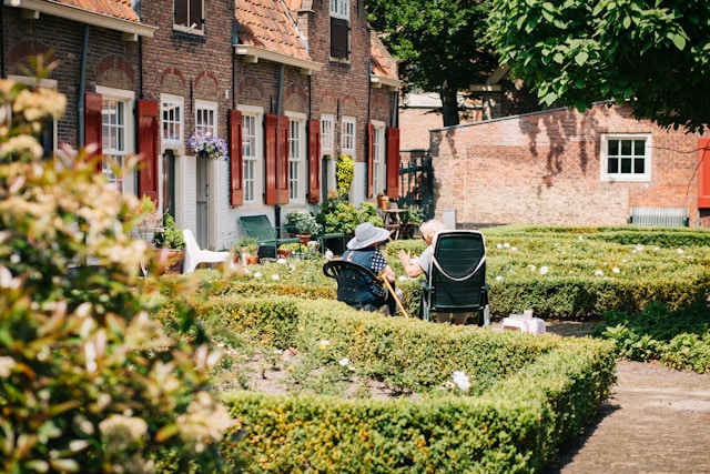 Two older women sitting at the graden outside the senior housing