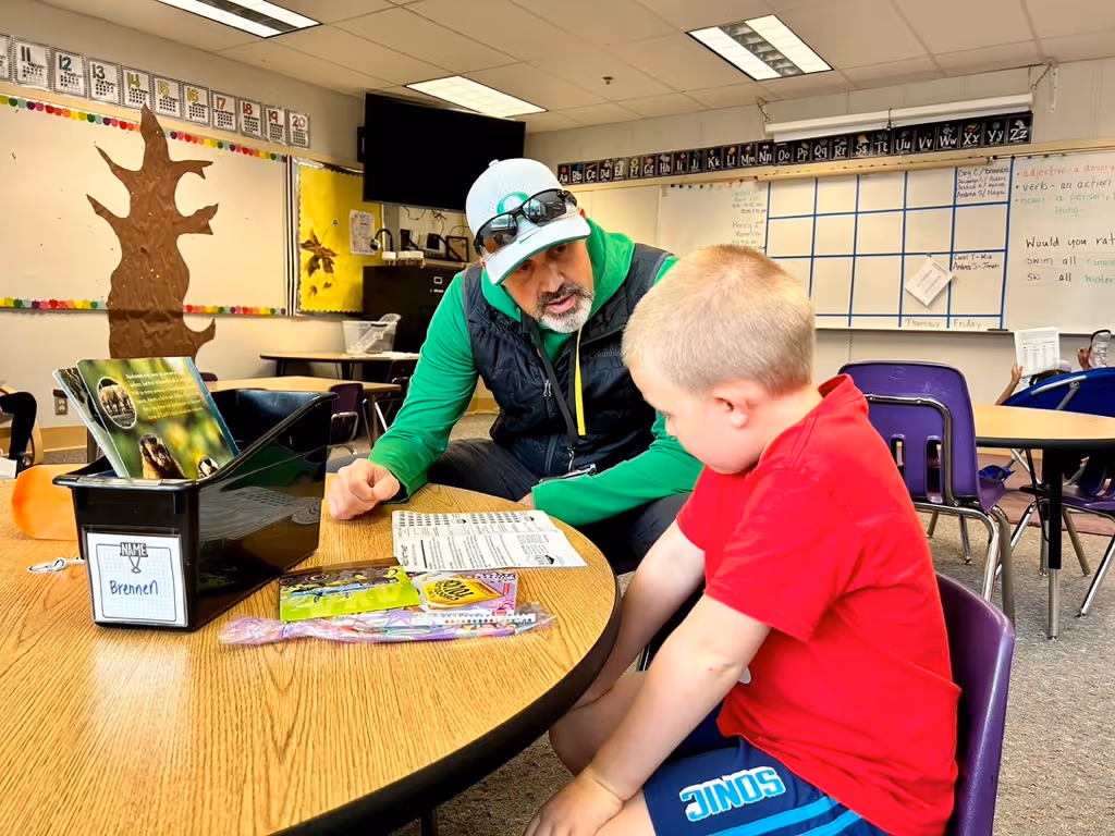 A male reading mentor reading with a boy around 8 years old in a classroom setting.