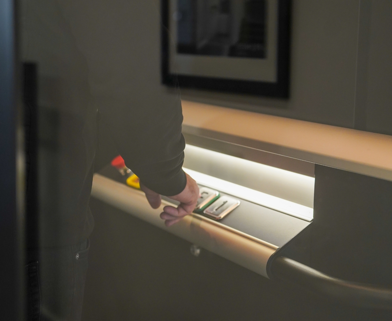 Person pressing buttons inside an elevator with illuminated control panel.