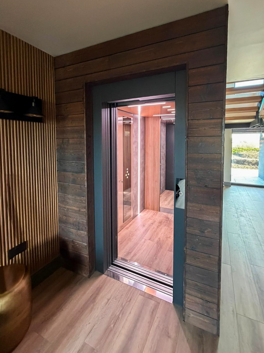 Modern residential eco home lift elevator with open doors, featuring wood paneling and interior LED lighting.