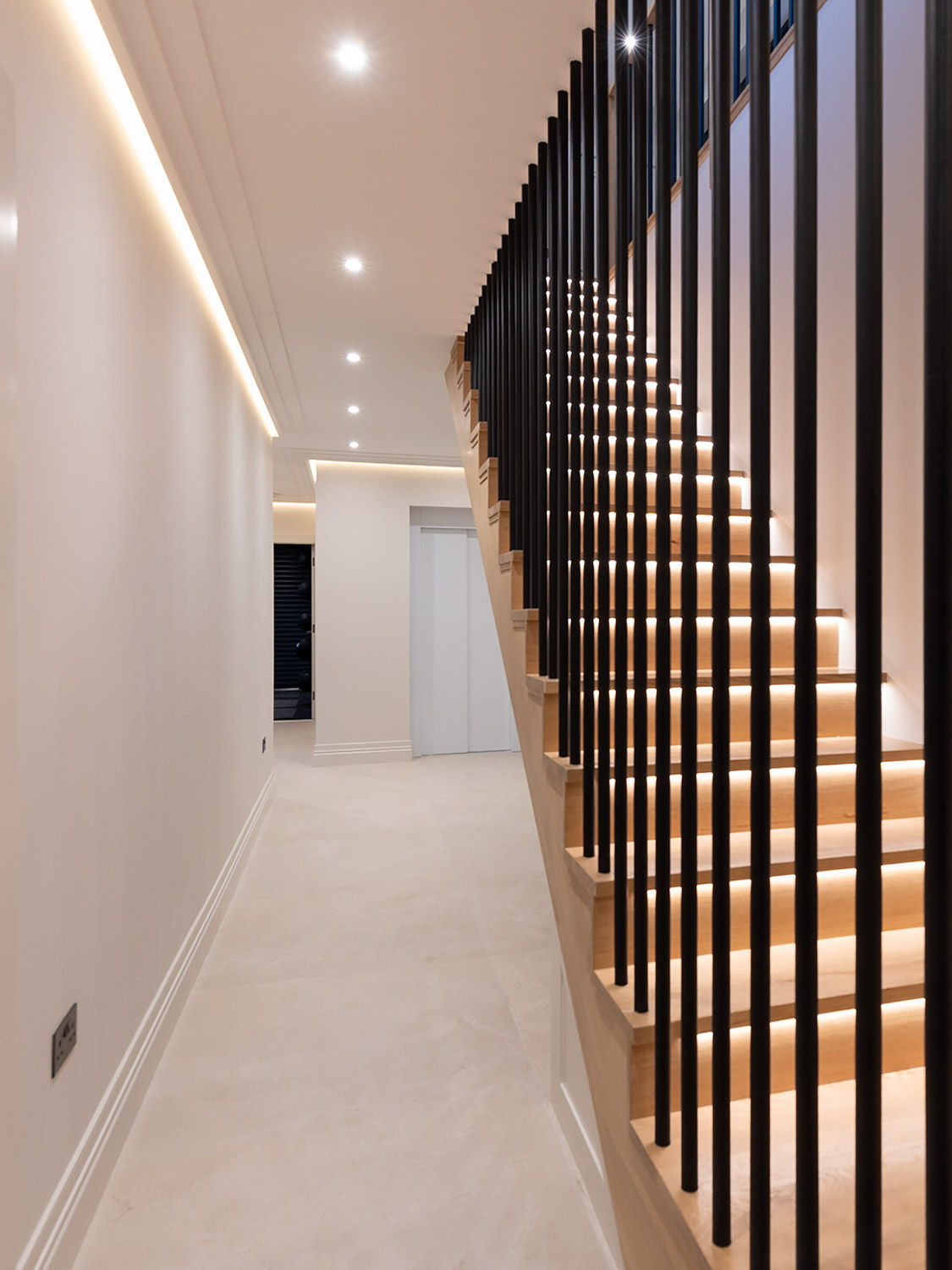 Contemporary hallway and illuminated staircase inside a Cork home, with the Eco+ home lift positioned beside the stairs.