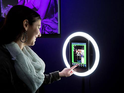 Woman touching a halo ring light testimonial video booth at an event