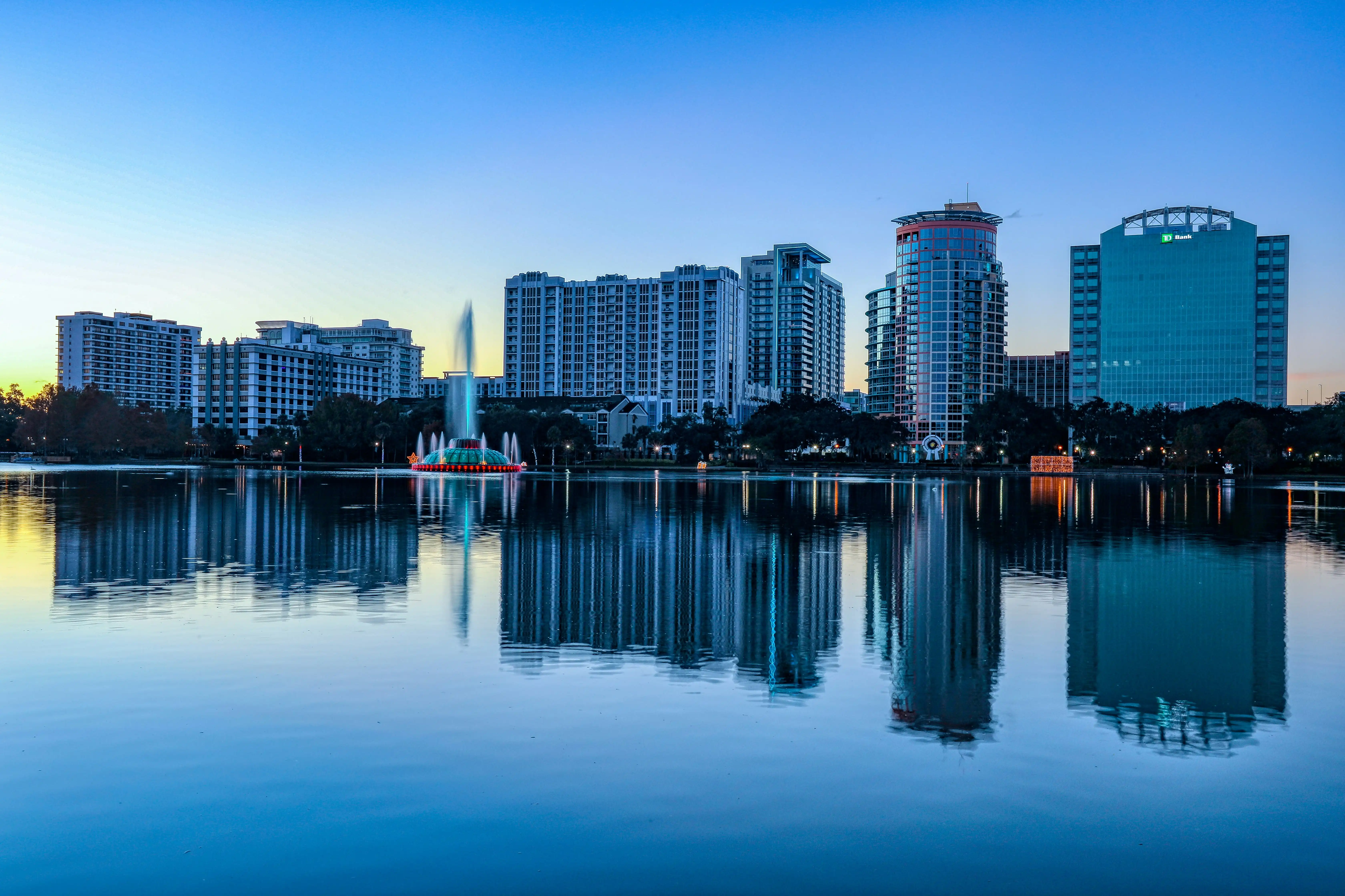 Orlando skyline reflected in Lake Eola at dusk with the fountain lit