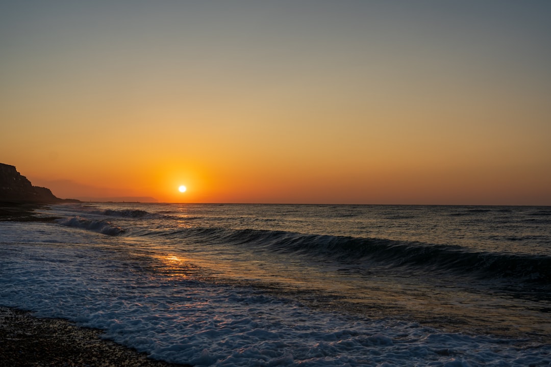 An orange sun, rising above the horizon, heralding the dawn of a new day in Autumn.