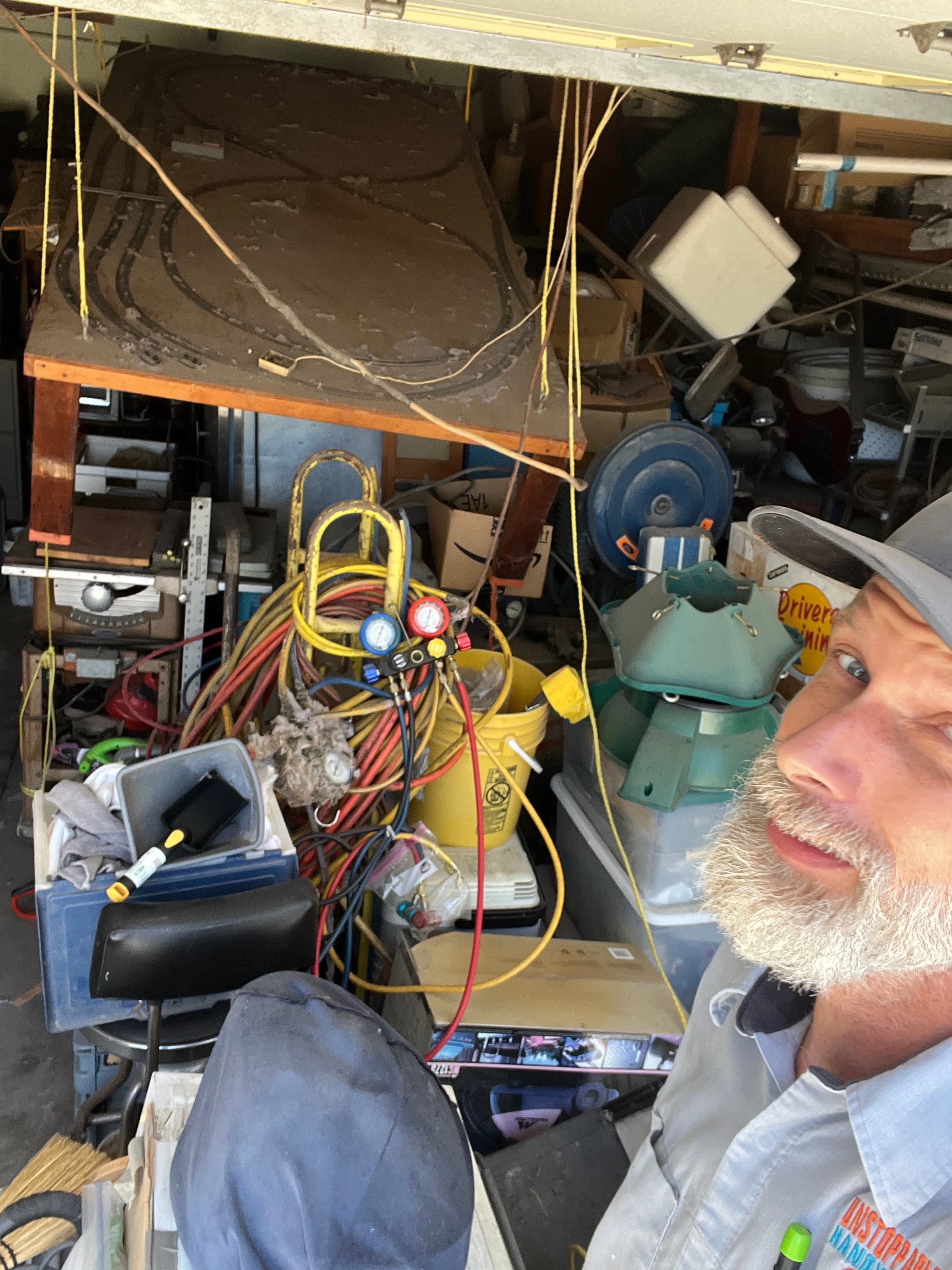 Chris beside a collapsed handmade model train table in a crowded Lemon Grove garage