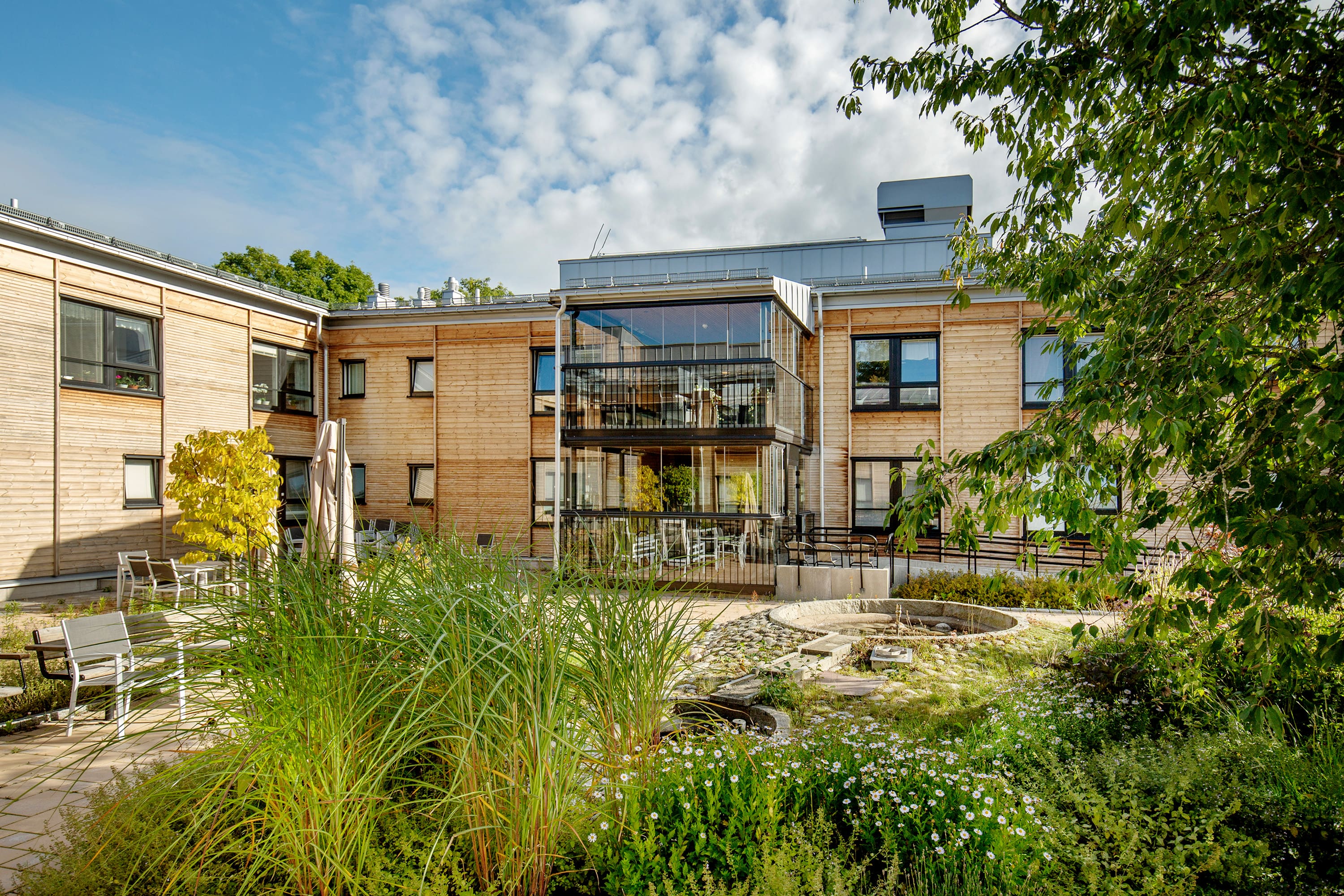 Ett foto från Allegårdens innergård med planteringar, stenlagda gångbanor och utemöbler.