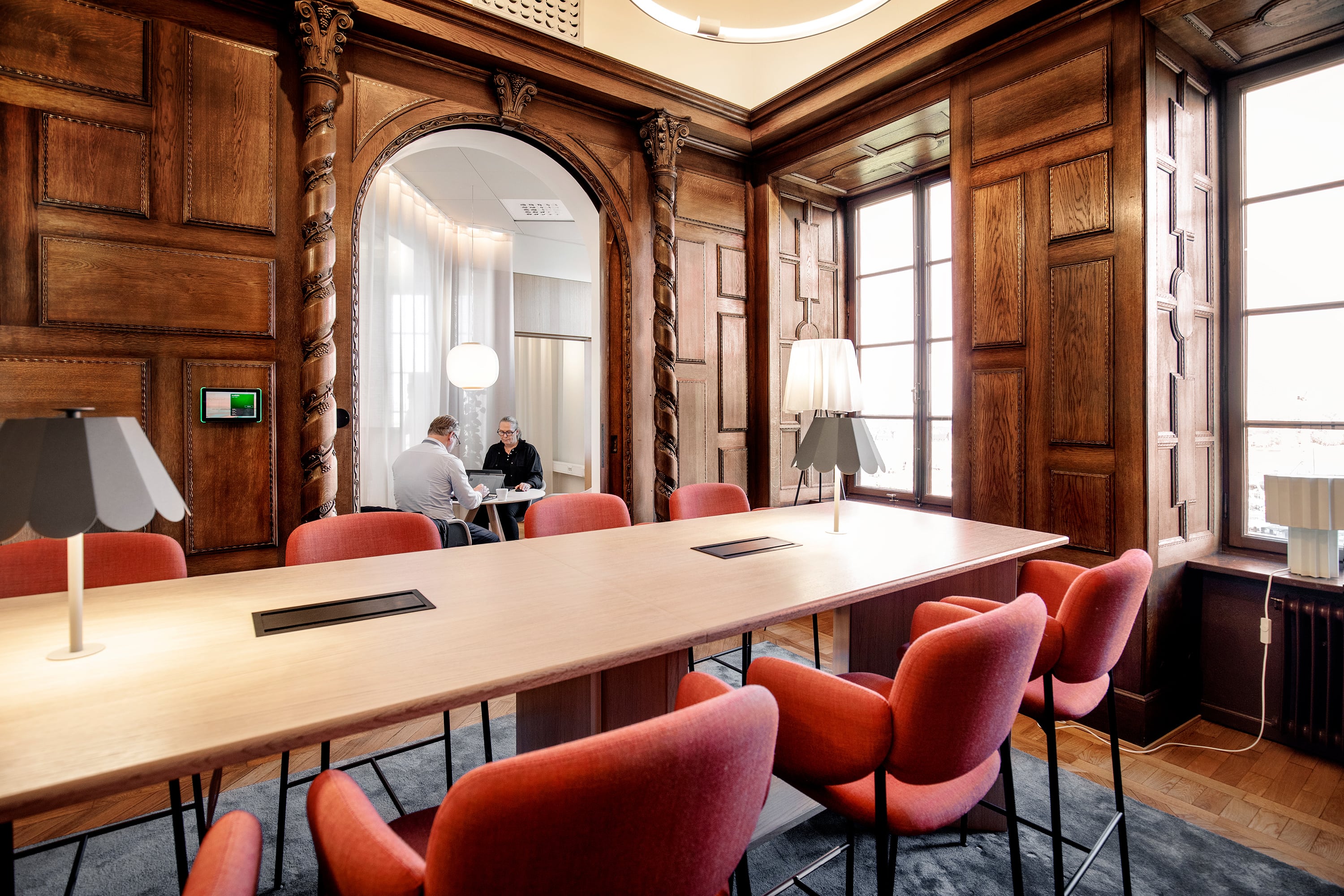 Foto från Höga loftet, ett kontor med träpaneler på väggarna, högt i tak och möblerat med varmt rosa armstolar.
