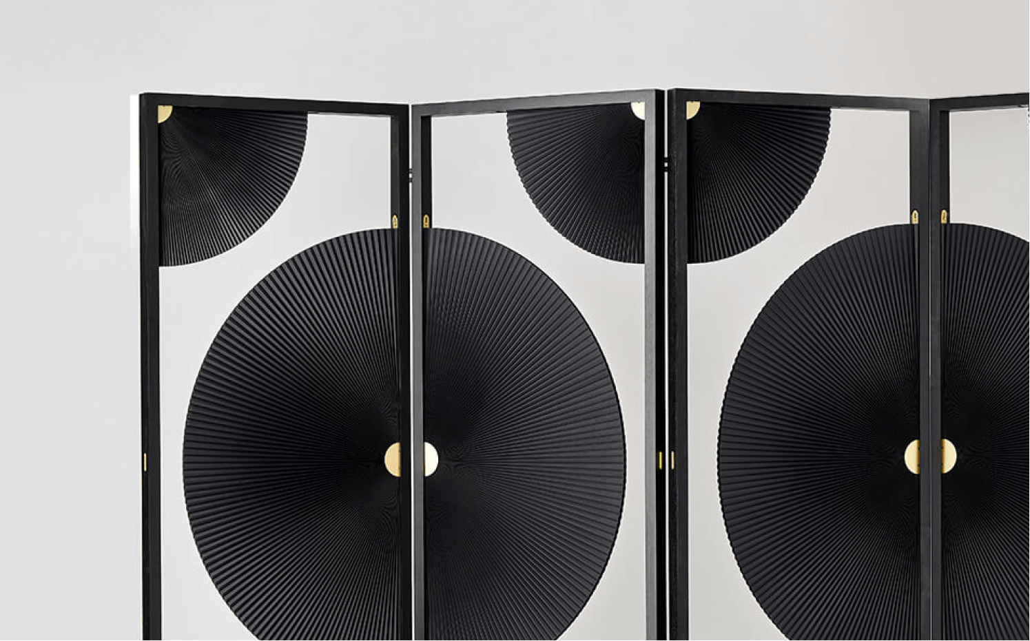 Black and white room divider with geometric circular pattern and gold accents on hinges.