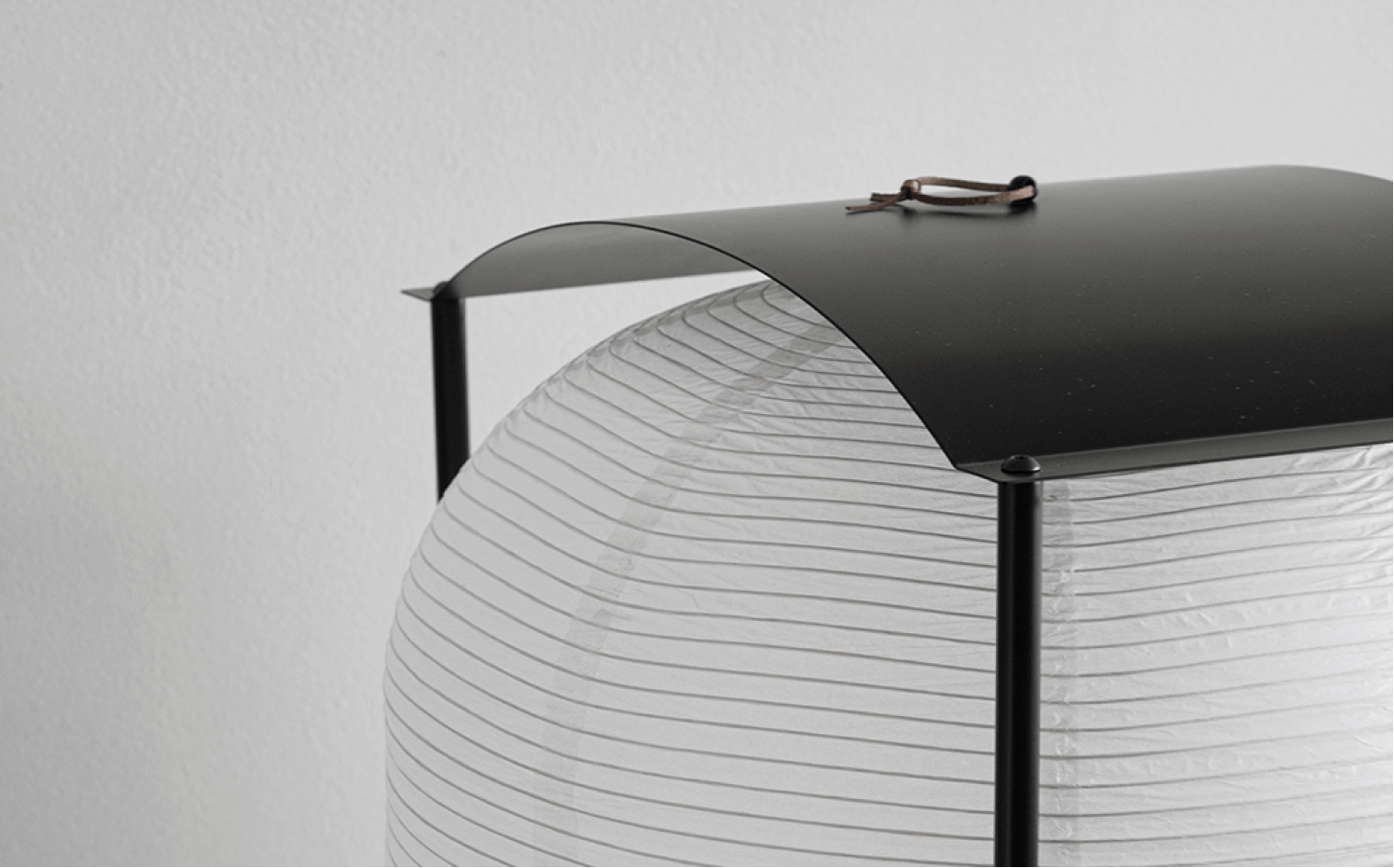 Close-up of a modern lantern with a white paper shade and black metal frame and top cover.