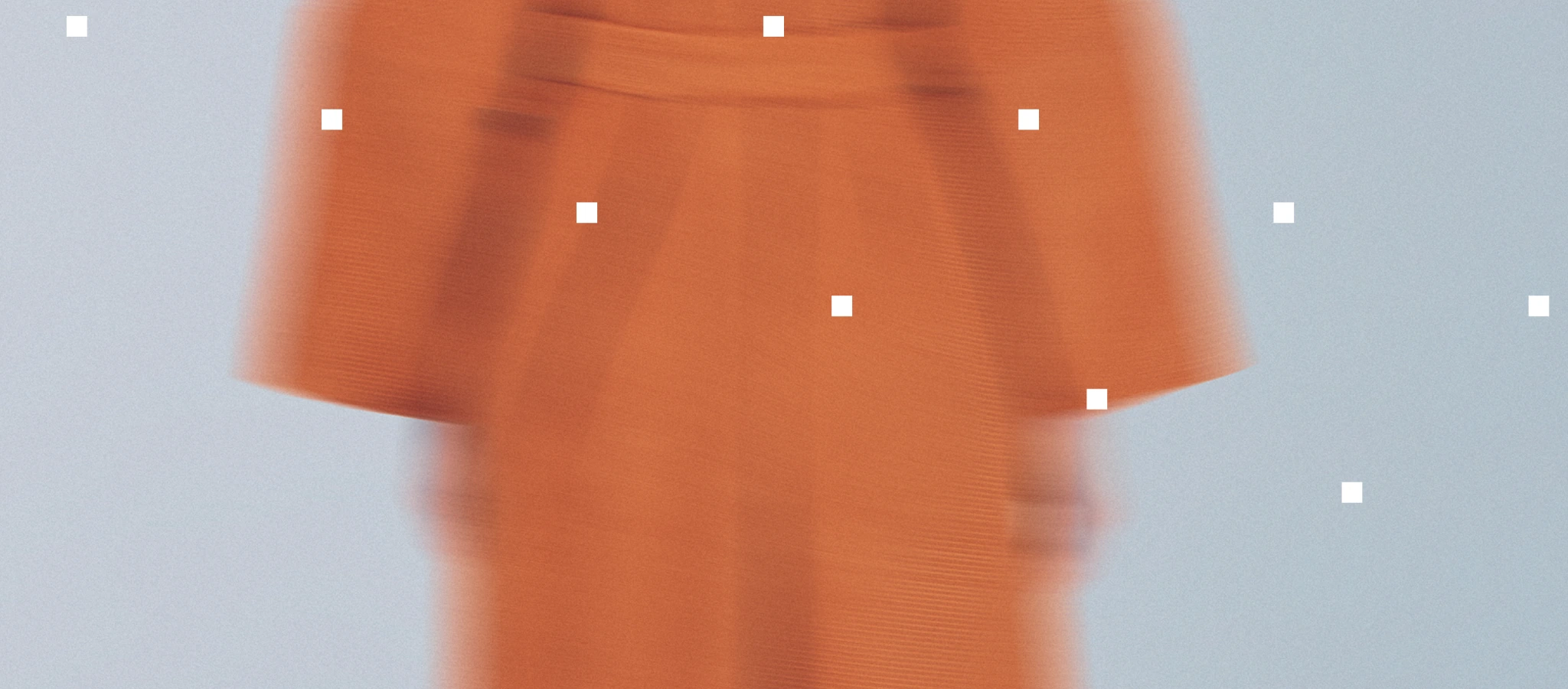 Blurred image of a person in an orange outfit against a light blue background with white squares.