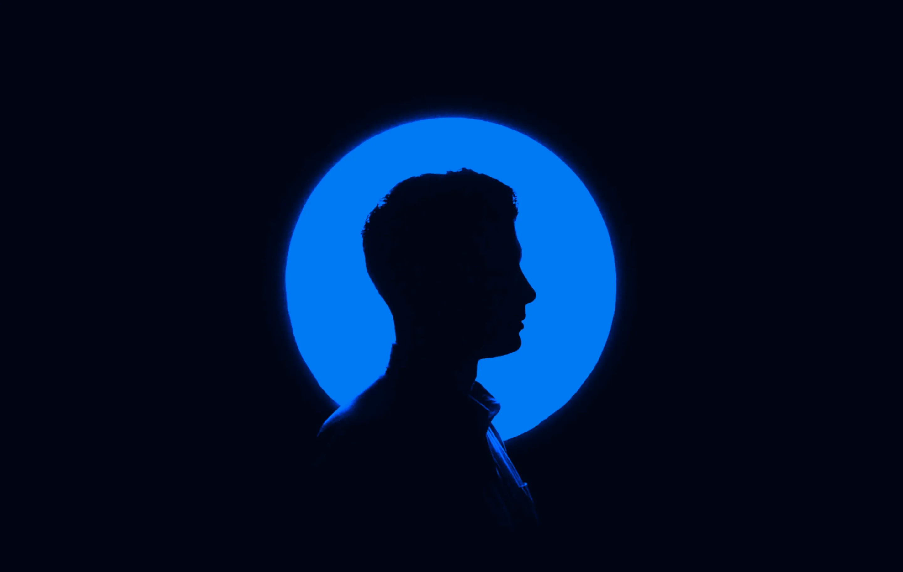 silhouette of a man in side profile cast as a shadow against a blue circle and black background