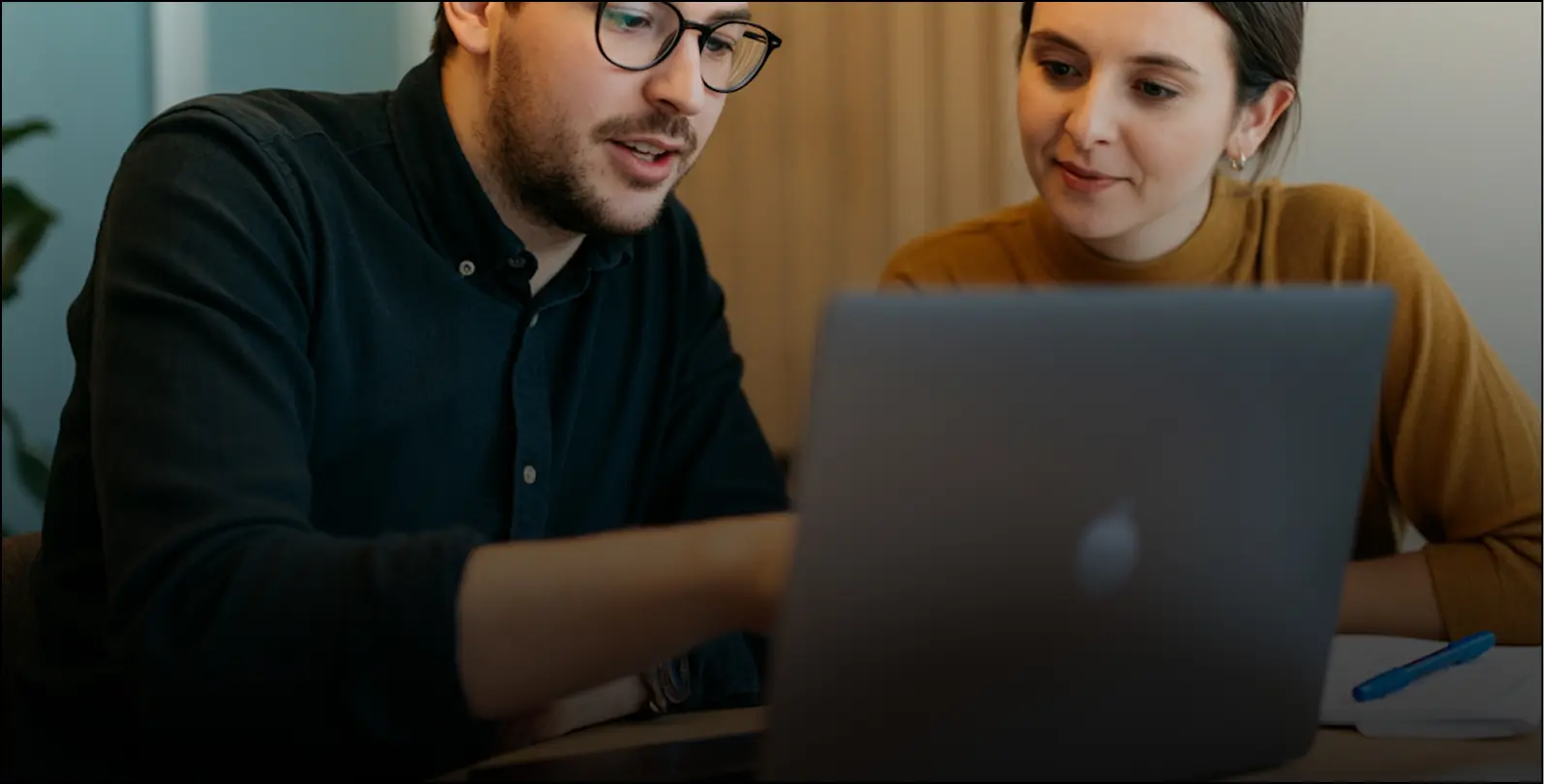 A man and woman looking at a laptop screen.