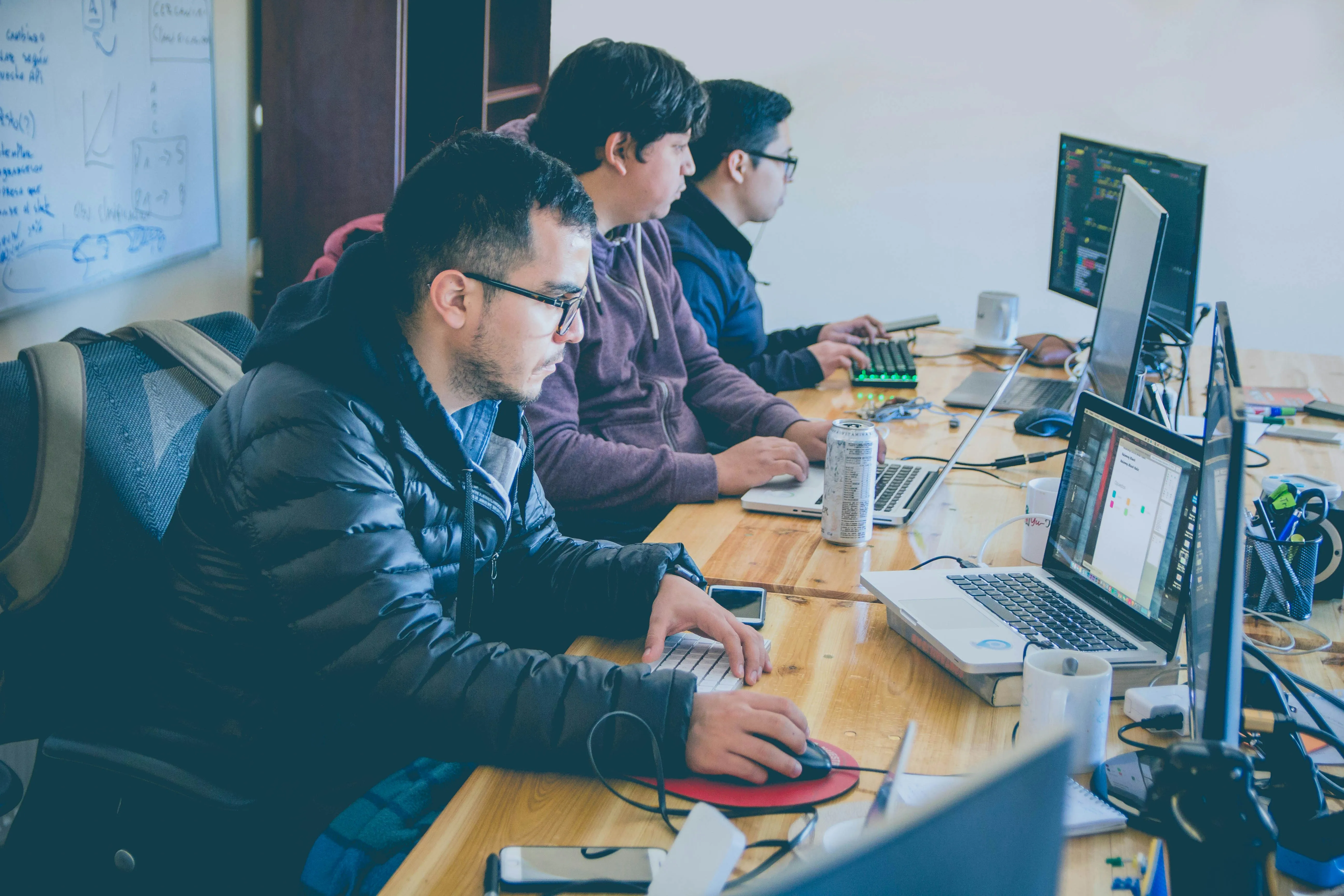 A group of men sitting at a table working on computers.