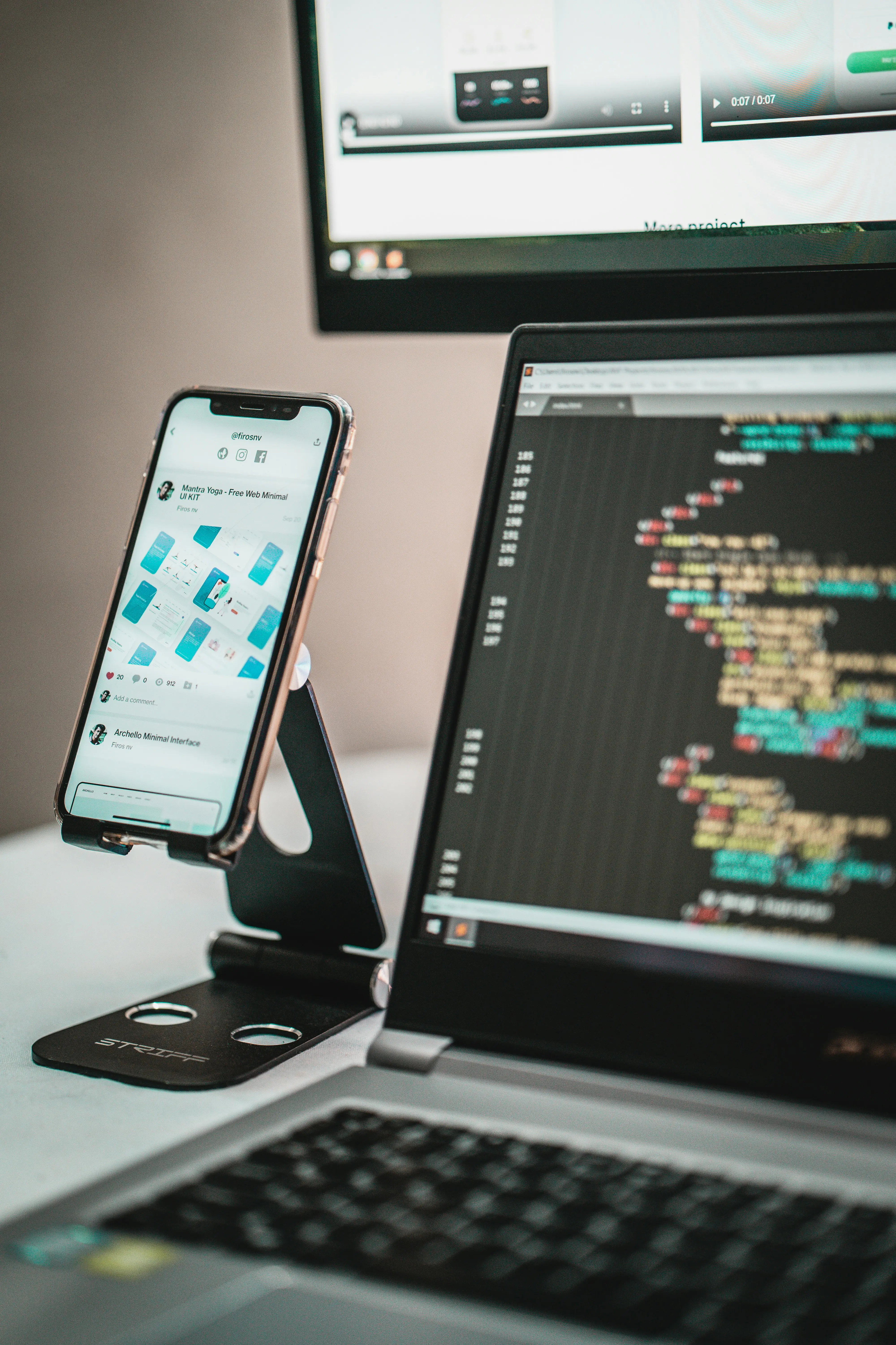 A cell phone and a laptop on a desk.