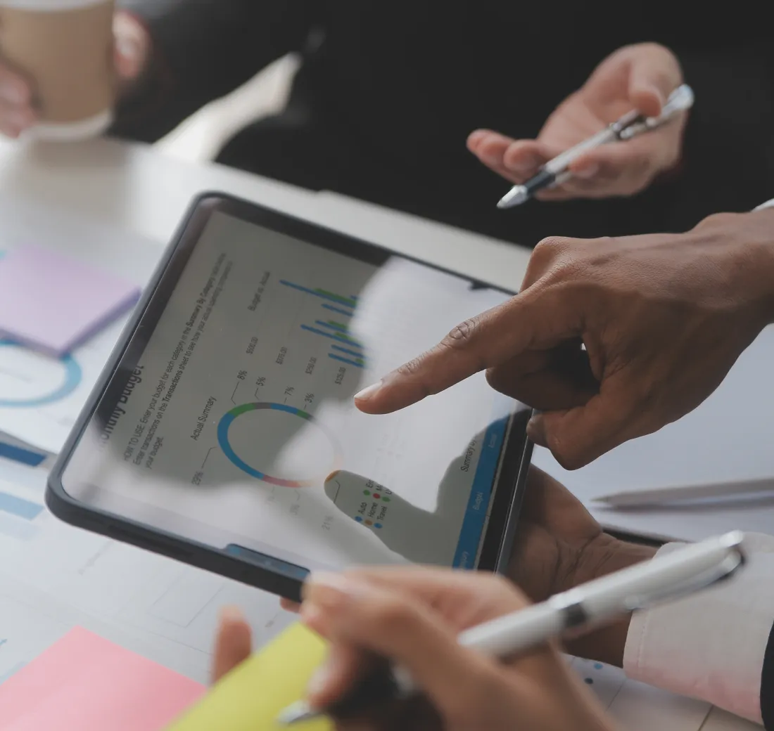 A group of people sitting around a table with a tablet.