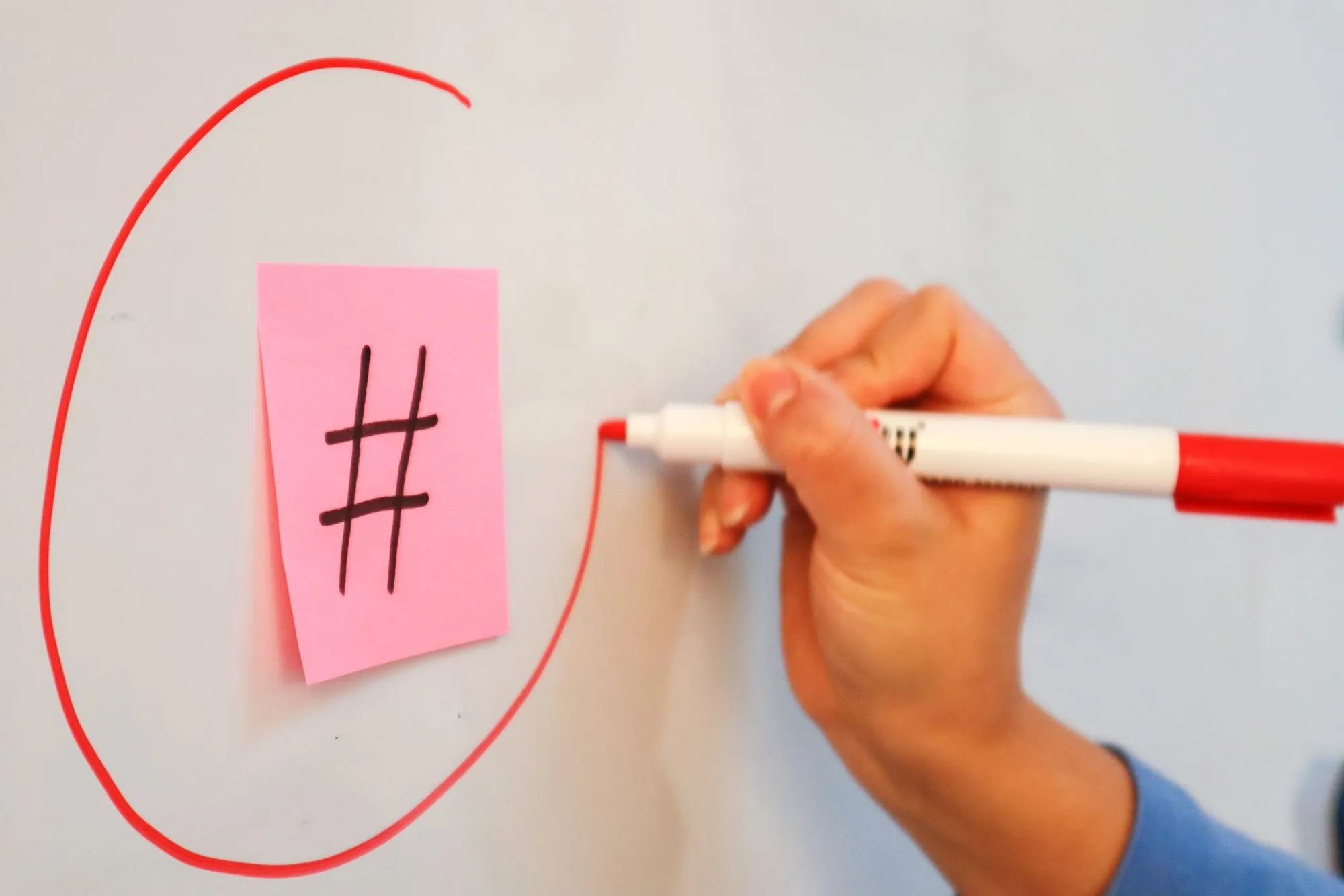 A hand drawing a red circle around one note on a whiteboard