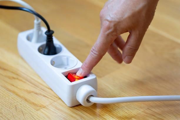 Pressing the red button of a white power strip on wooden background Pressing red button of a white power strip on wooden background - energy saving Switch Power Cords stock pictures, royalty-free photos & images
