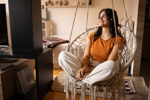 a lady comfortably sitting in a cosy hanging chair