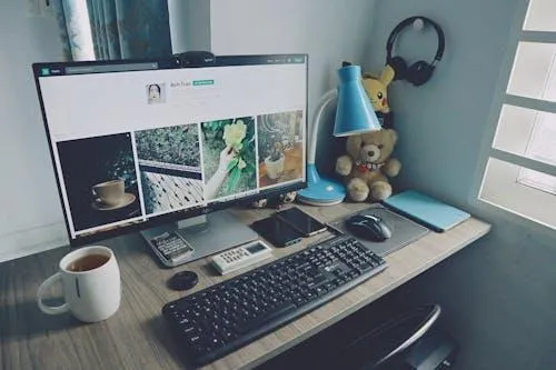 Free A tidy home office desk setup with a computer, keyboard, and personal items, creating a cozy work atmosphere. Stock Photo