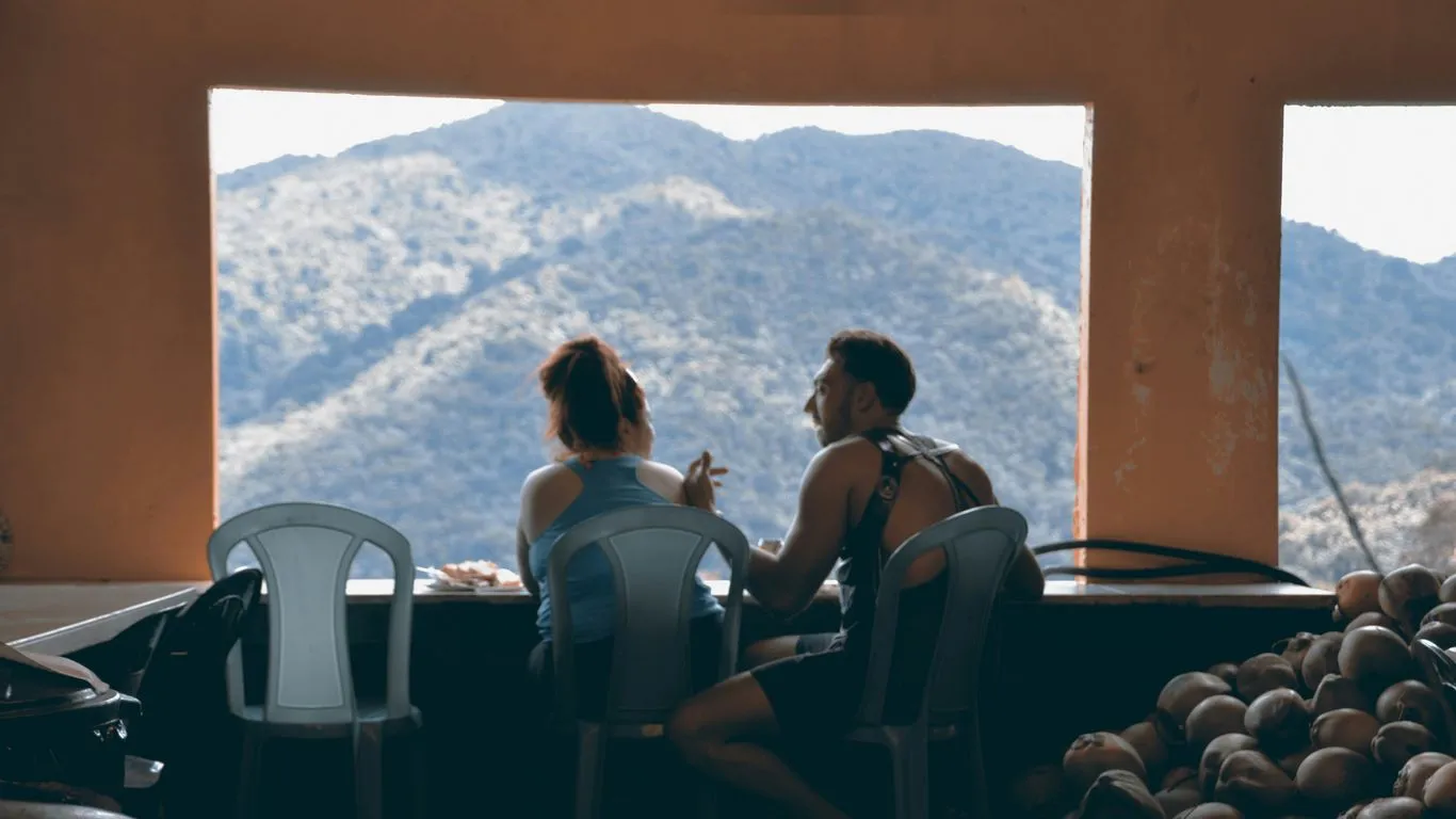 a man and a woman sitting at a table in front of a window