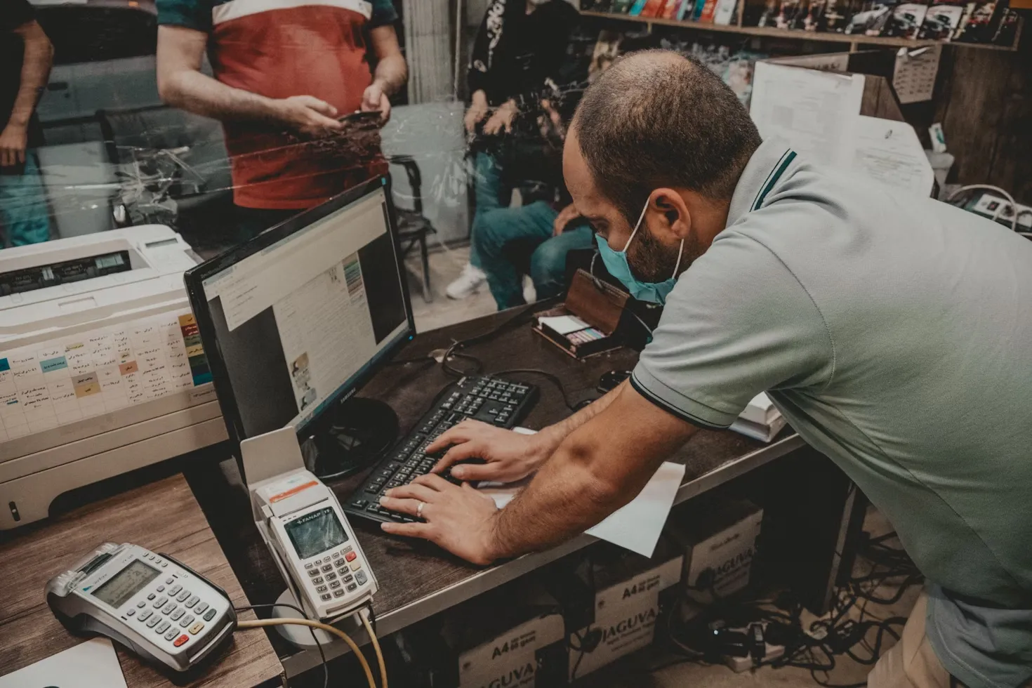 Shopkeeper using a laptop with a face mask on