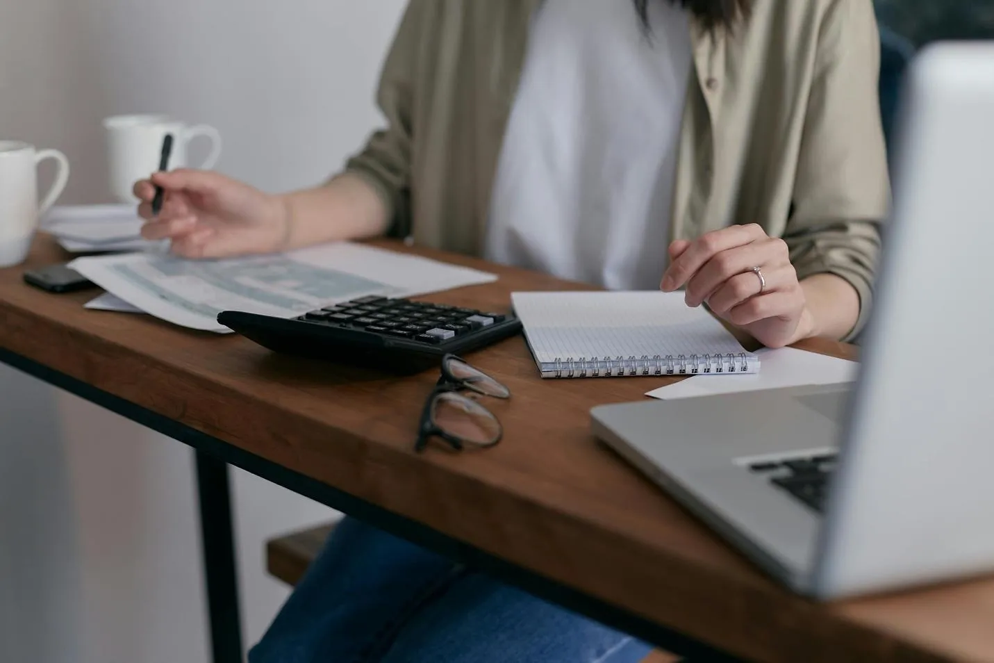 A laptop, calculator, and notepad on a desk