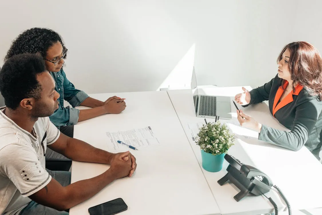 A couple sat at a desk with a women
