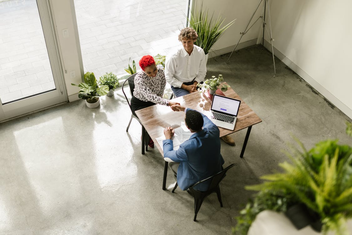 A man and women sat at a desk shaking hands