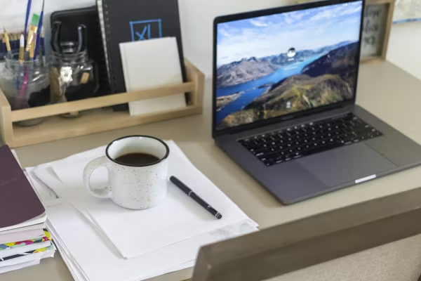 MacBook, cup of coffee, and stationary on a desk