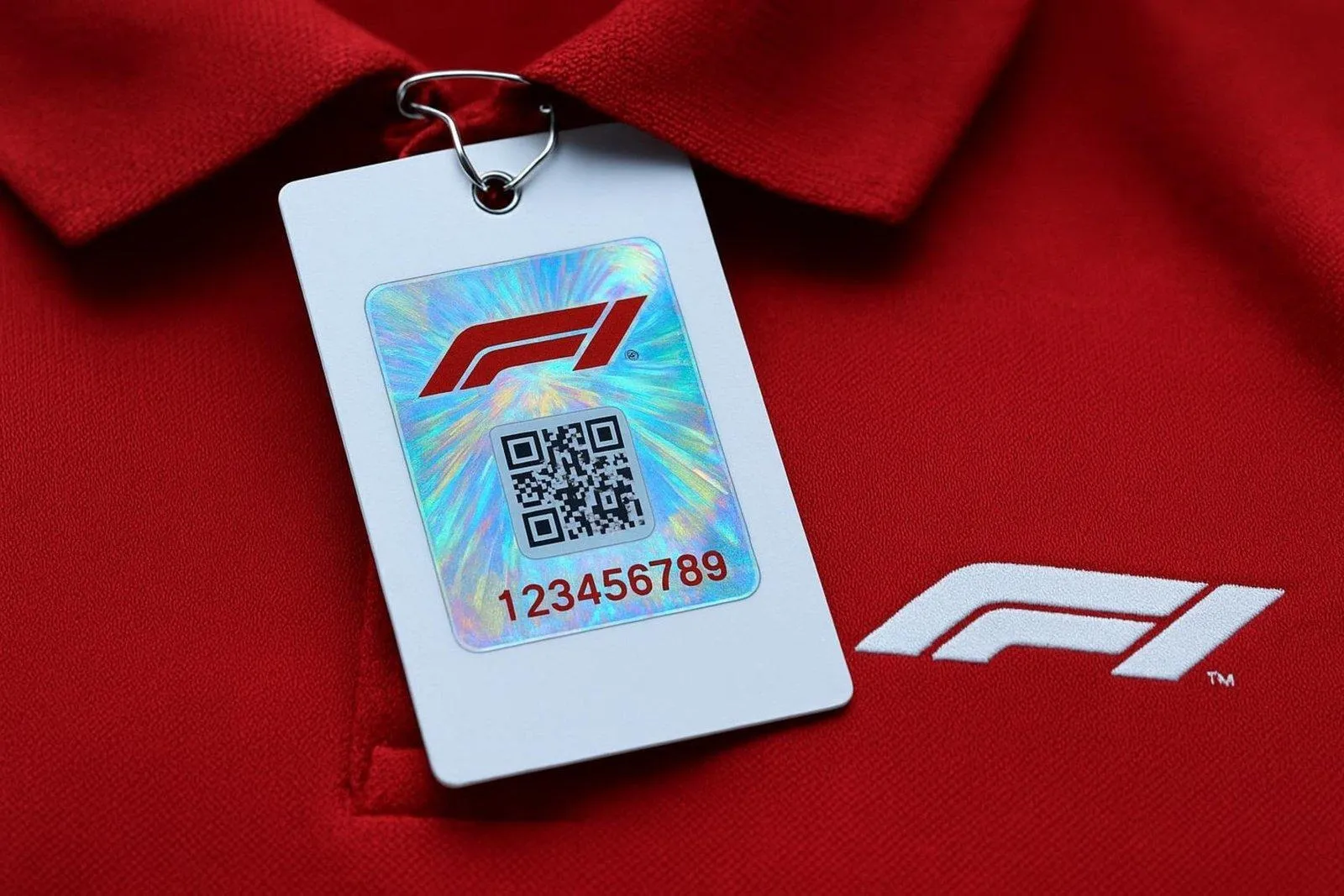 Close-up of official Formula 1 merchandise tag showing holographic sticker QR code and serial number on a red polo shirt.