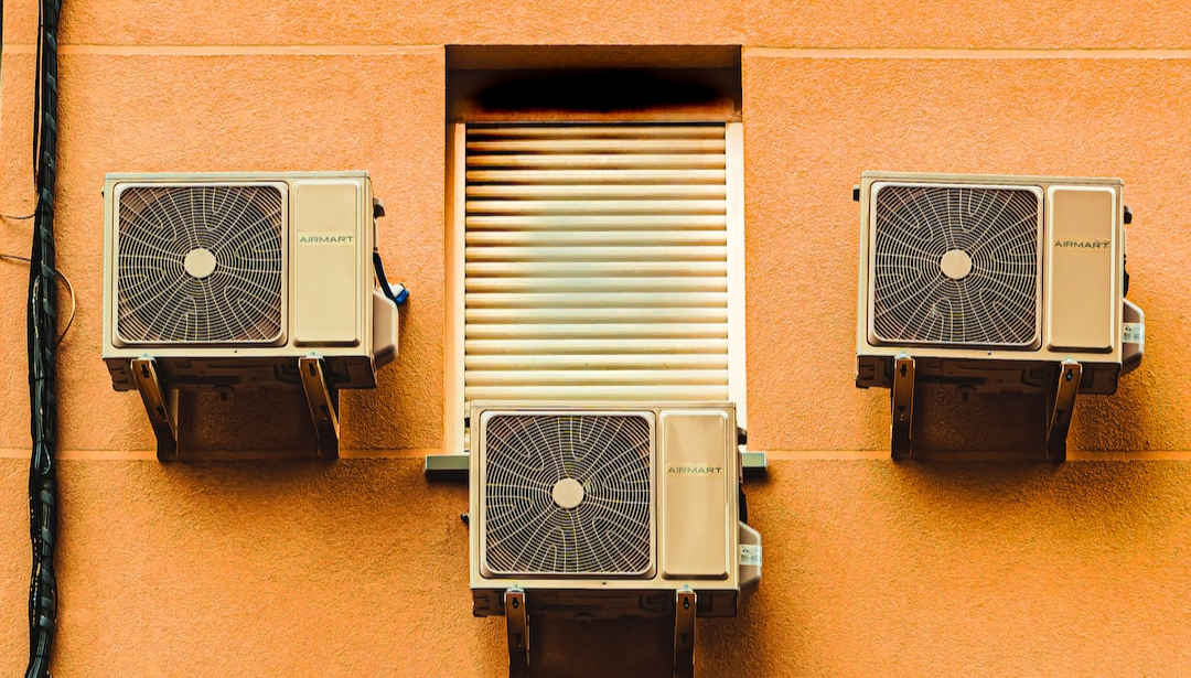 An air filter with three air conditioners on an orange wall.