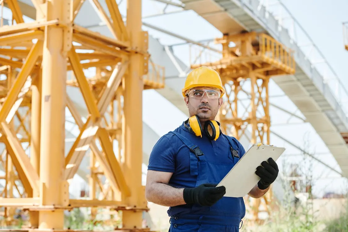Man in yellow hat holding a white board