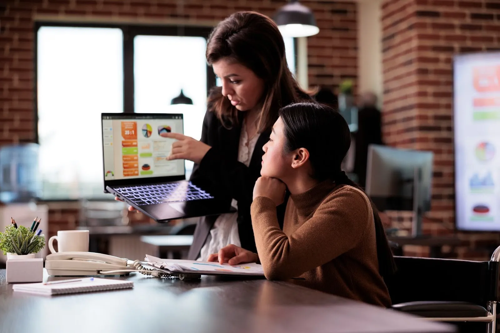Two women looking at a MacBook