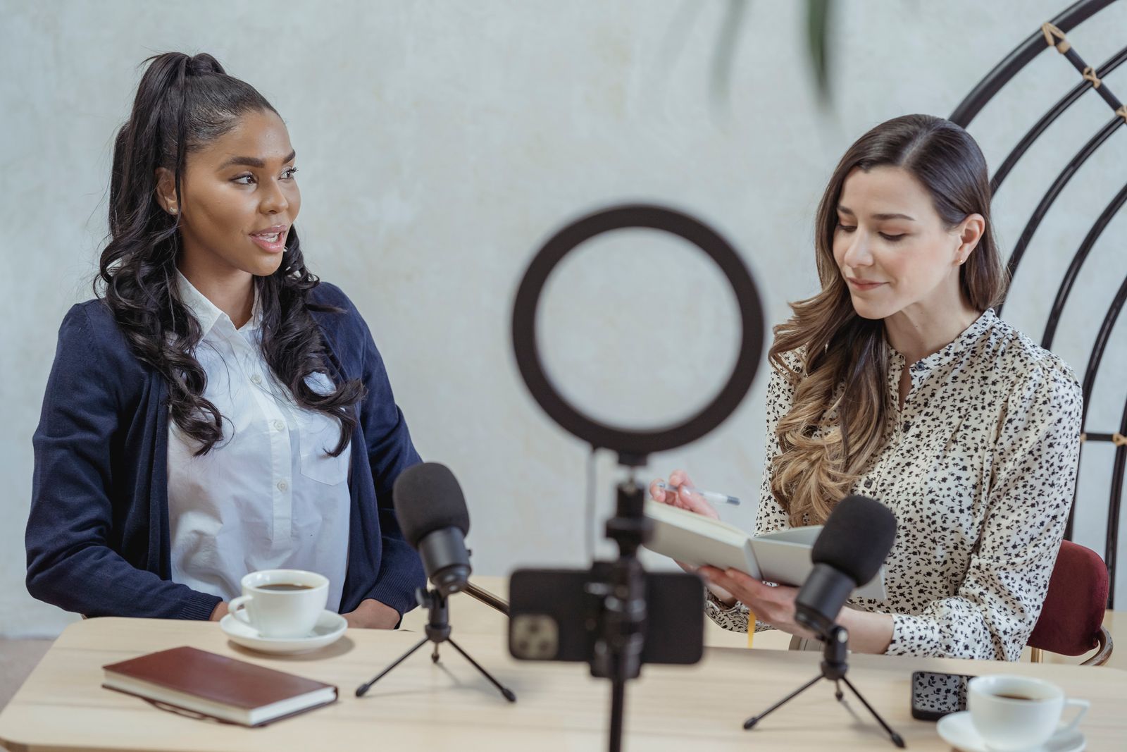 Two women recording an interview with microphones, one taking notes