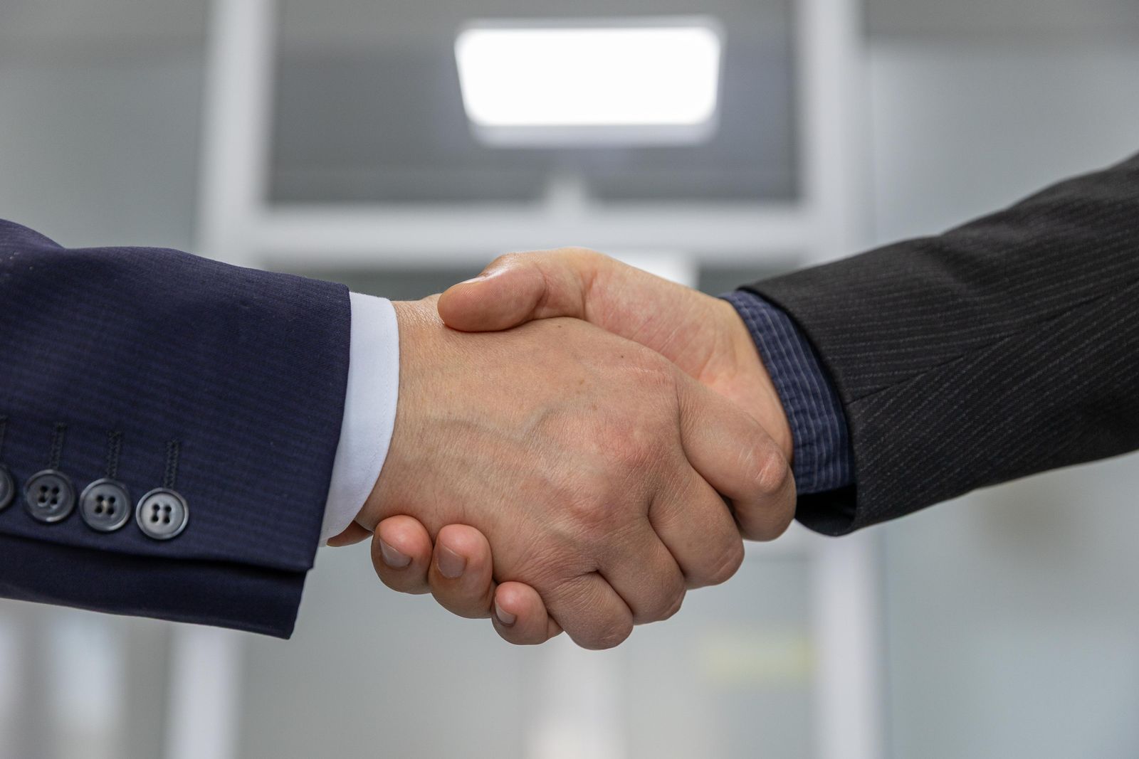 Two people in suits shaking hands in an office