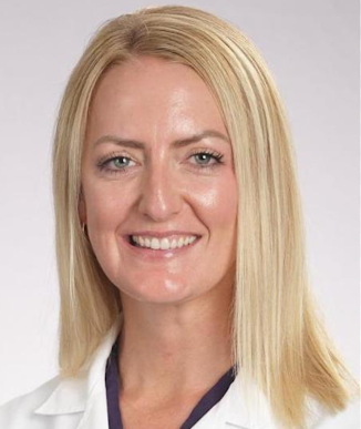 Smiling woman with straight blonde hair wearing a white lab coat over a navy top.