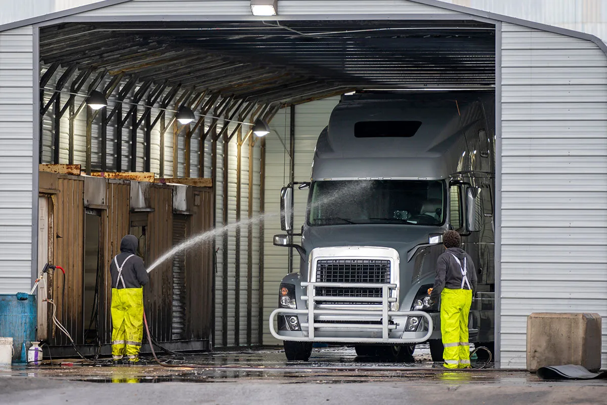 Pacific North Washed team performing low-pressure fleet cleaning on a lineup of service vehicles in a commercial lot.
