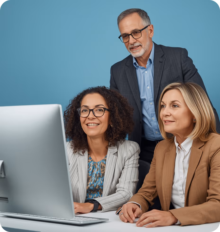 Three business professionals, two women and one man, working together and looking at a desktop computer screen.