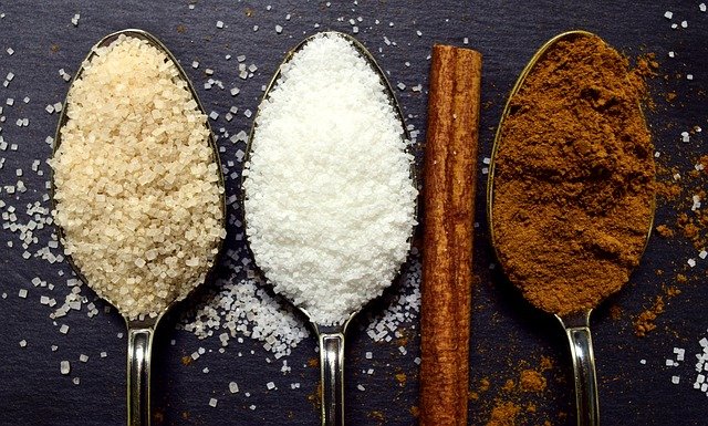 Mehrere Löffel mit verschiedenen Sorten Zucker und Zimt