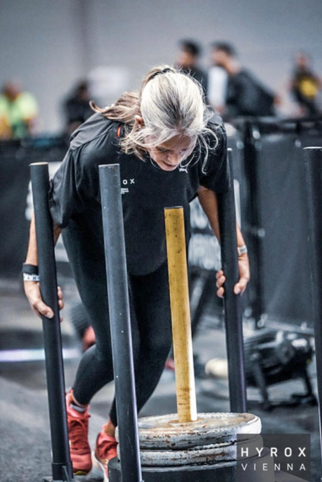 Eine Frau in Trainingskleidung rennt vor einer Betonmauer.
