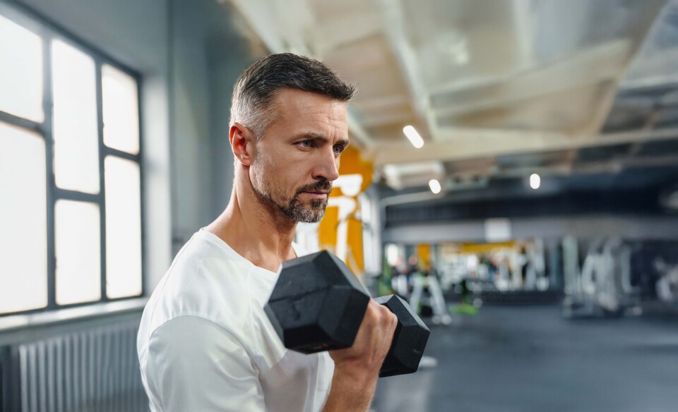 Eine mittelalter Mann, der einen Bizeps-Curl mit einer Kurzhantel macht.