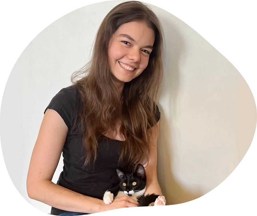 Portrait von Dr. med. vet. Denise Riggers, lachend,  mit einer schwarz-weißen Katze auf dem Arm.