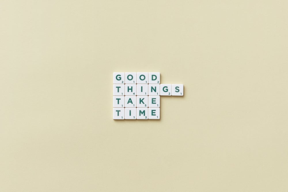 White Scrabble tiles reading, "Good things take time."