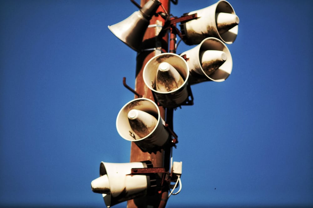 Several loud speakers on a telephone pole.