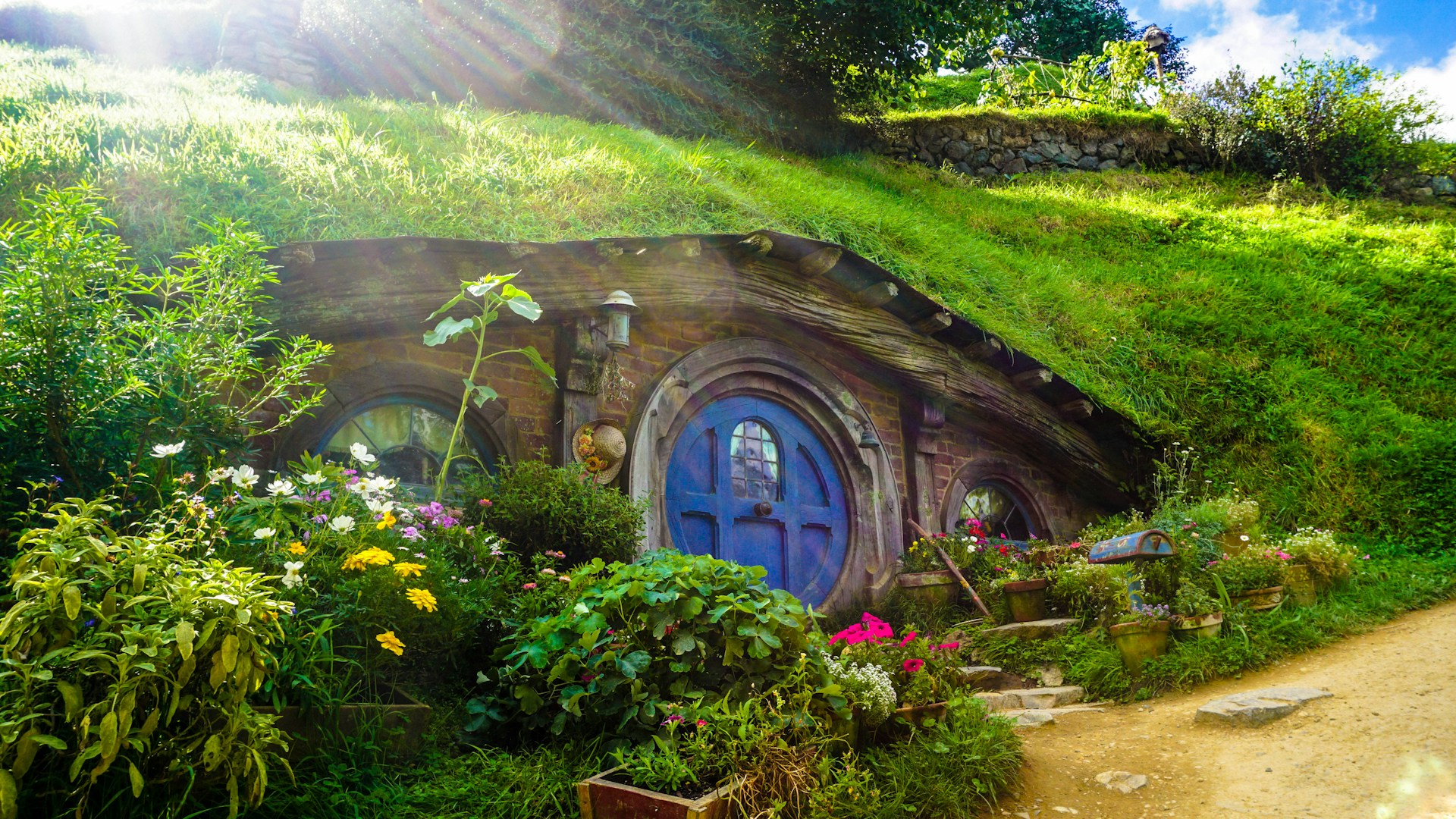 A hobbit house with a round blue door built into a green hillside.