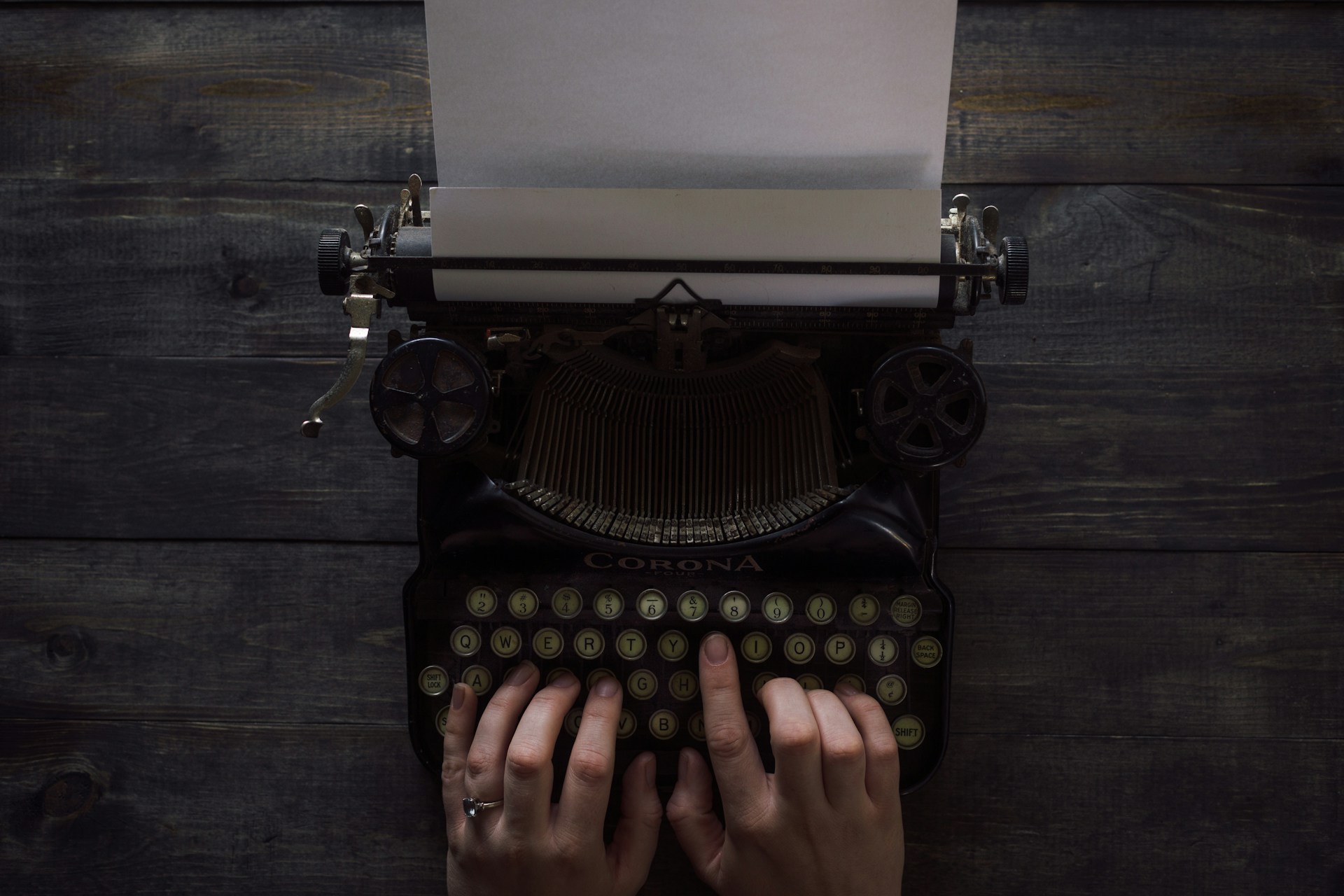 Hands type on a black antique typewriter.