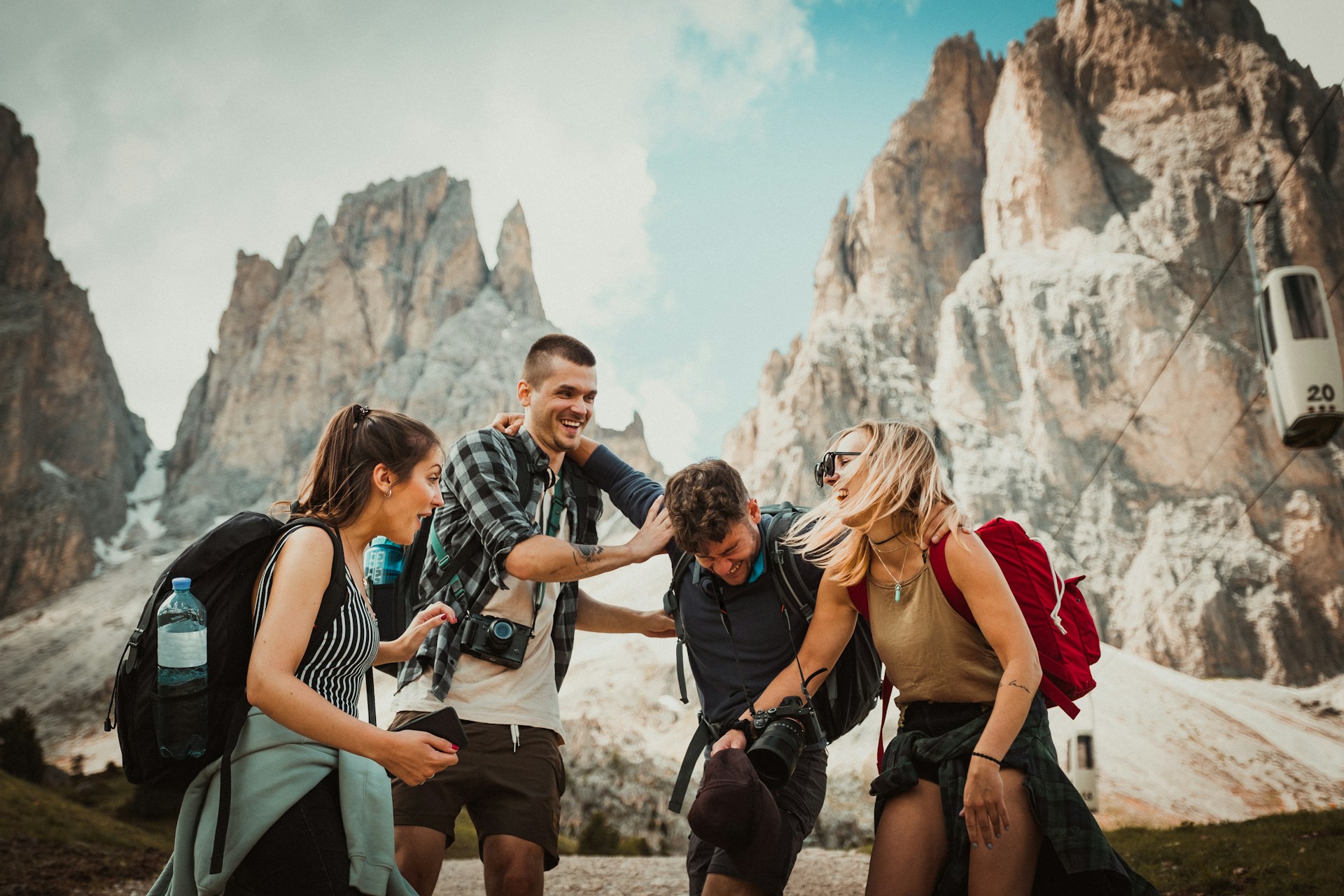 A group of four friends laugh together in front of cool rock formations.