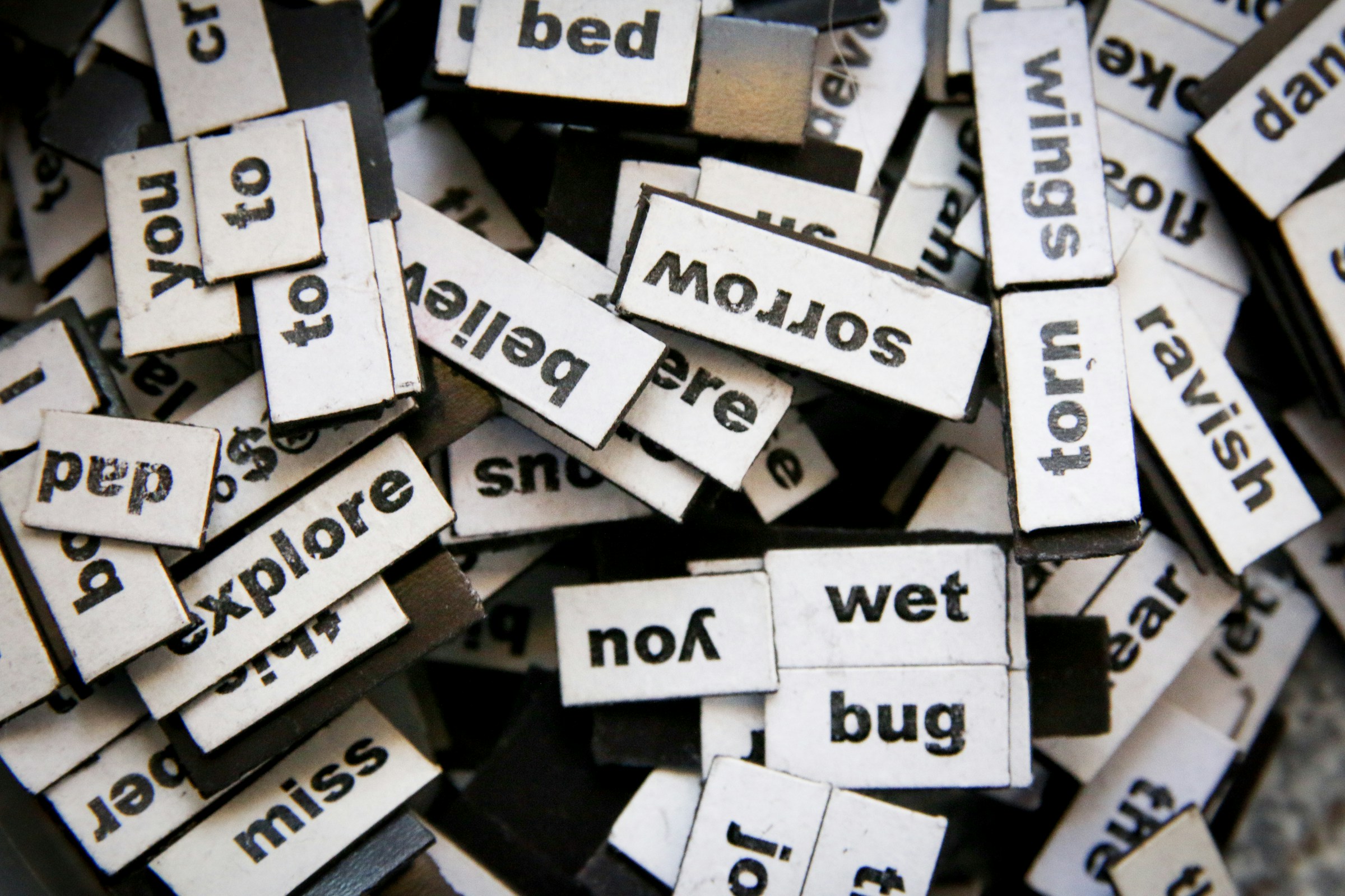 A pile of magnetic poetry tiles with different words on them.